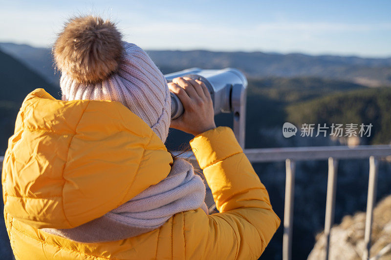 观点。独自旅行者在一个美丽的全景从高山上。冬天阳光明媚的户外享受。旅游目的地。用观光望远镜看。全景望远镜。