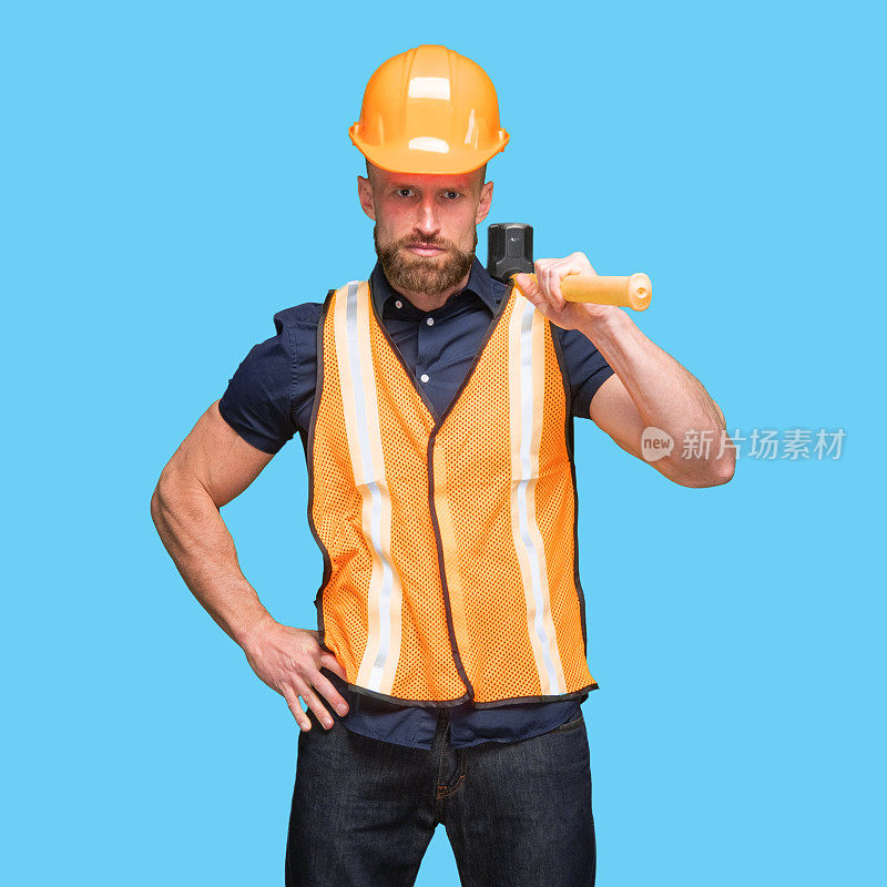 白人男性建筑工人站着，穿着反光衣服，拿着工作工具