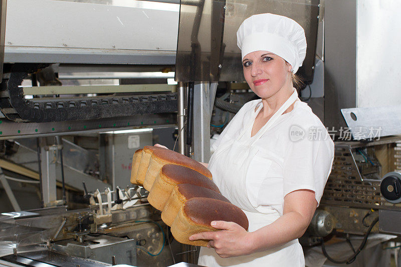 生产面包的工厂工人手里拿着面包。有一个工人的面包工厂