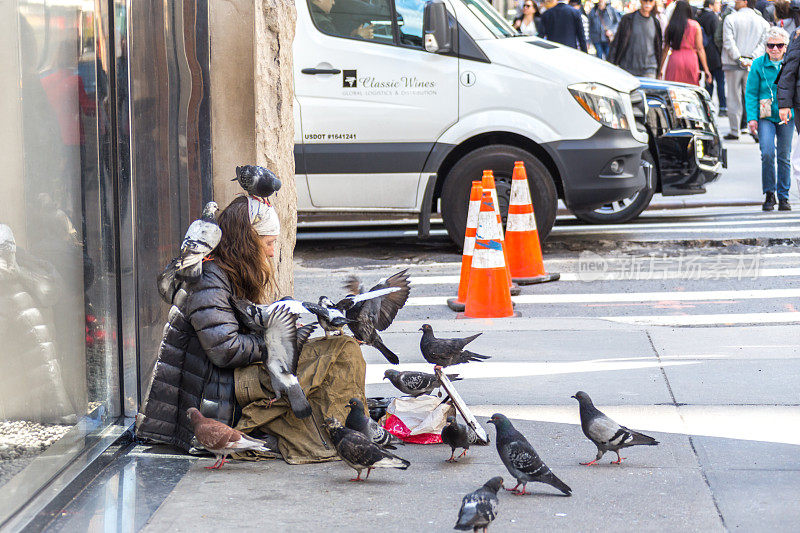 年轻无家可归的女人带着许多鸽子在纽约第五大道寻求路人的施舍