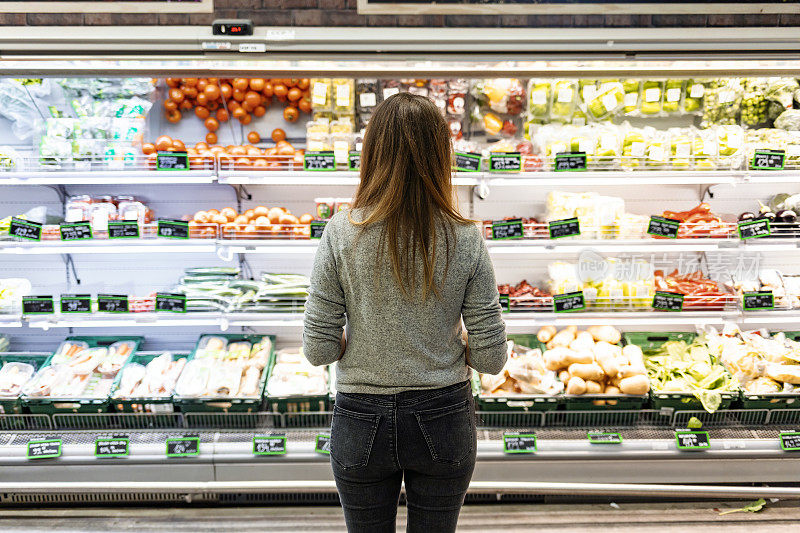 年轻女子在超市里看新鲜蔬菜