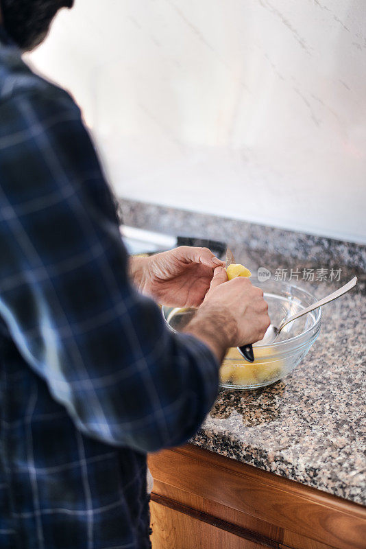 隔离烹饪:一名男子将土豆切好，放入沙拉碗中