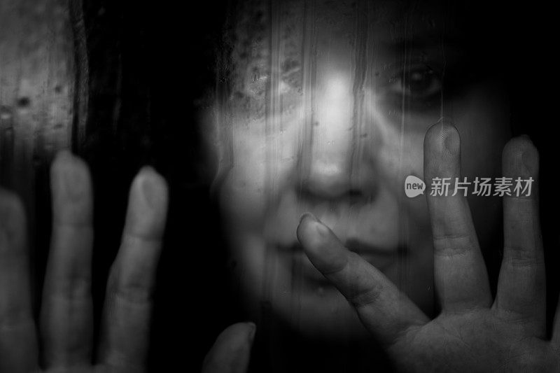 沮丧的女人望着下雨的窗外