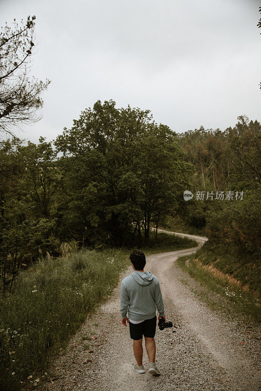 一个拿着单反相机的年轻人的后视图