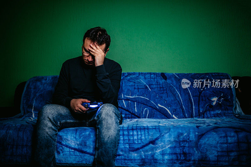 一个人玩电子游戏的悲伤男人