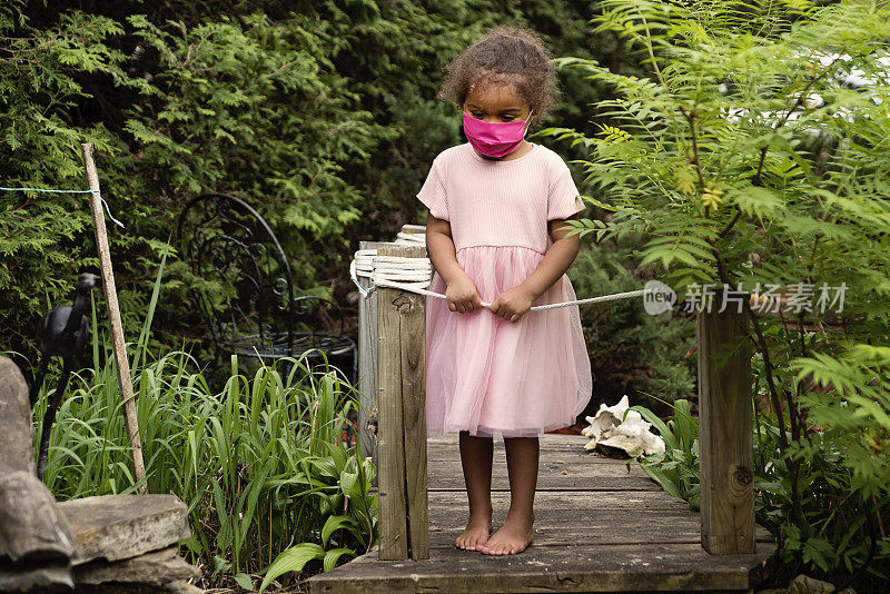 蹒跚学步的小女孩戴着时尚的粉色防护面膜。