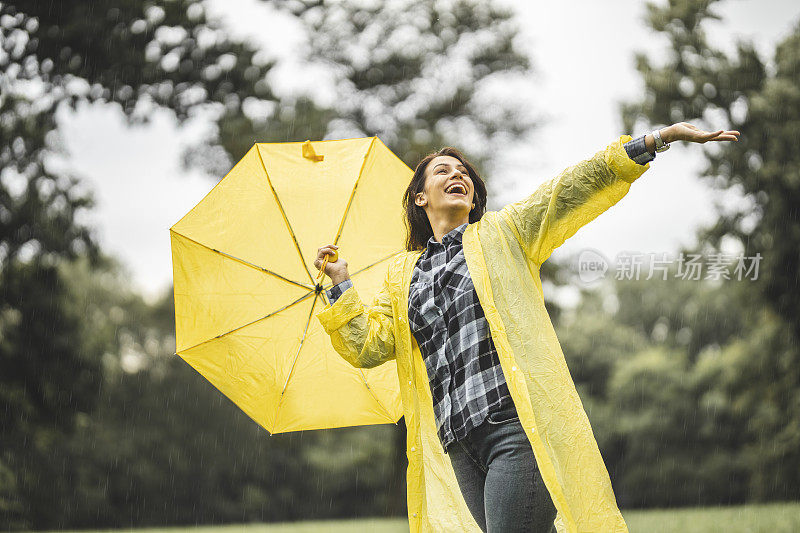 快乐的女人微笑着行走在雨天