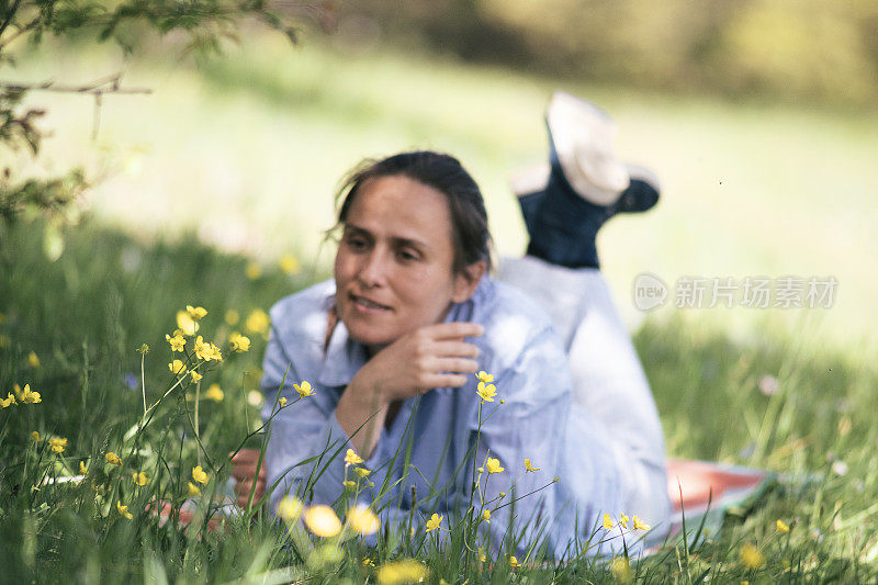 回归自然。独自旅行的女人用智能手机拍照。一个快乐的年轻女性游客在自然中放松。在阳光明媚的日子里，在绿草如茵的户外享受。