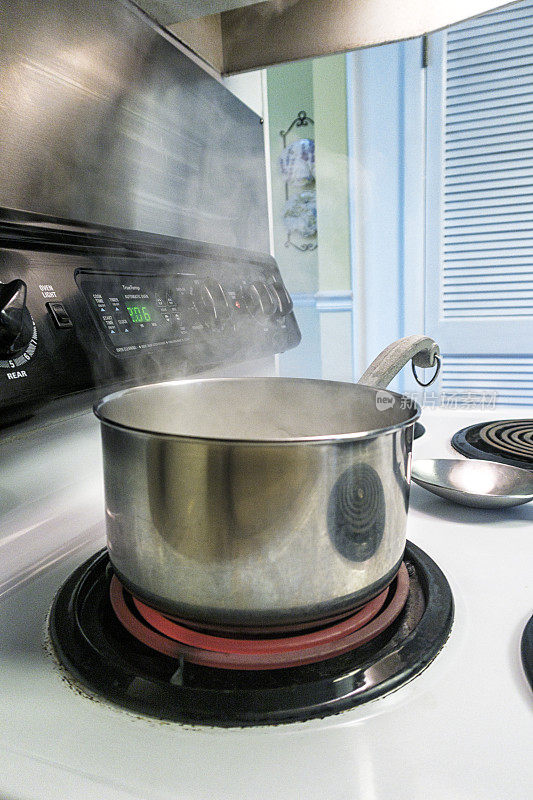 电炉上沸腾的水从锅中喷出旋转蒸汽