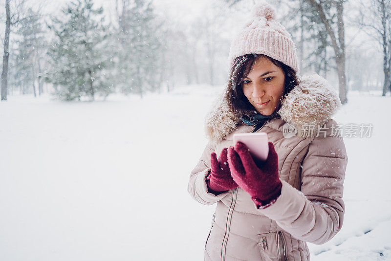 一个女人在雪地里查看社交媒体