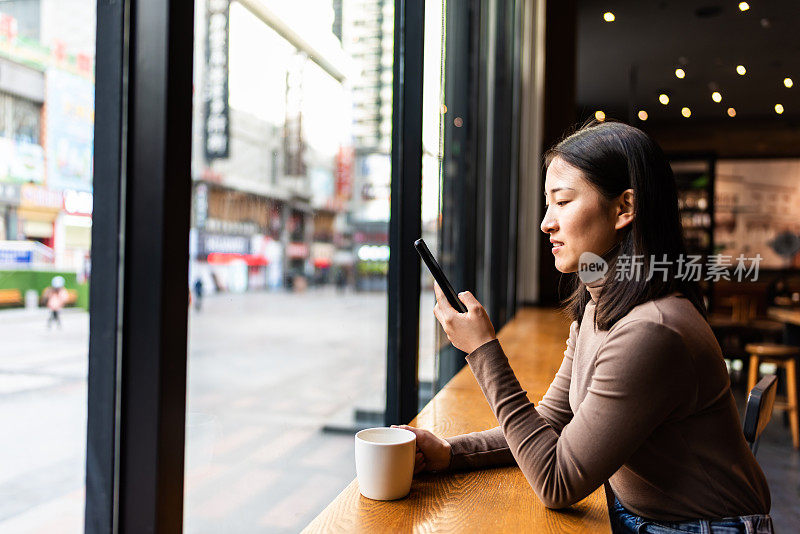 年轻的亚洲女性在咖啡店里使用智能手机