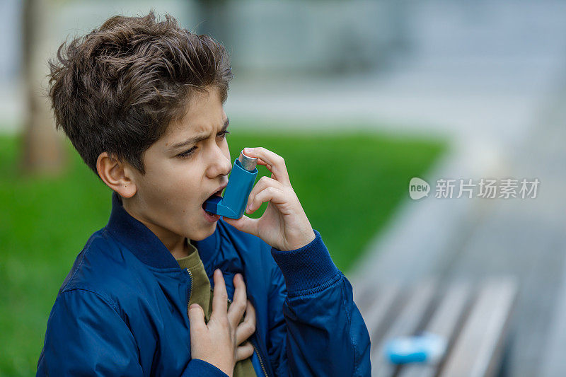 小男孩在公园里使用哮喘吸入器。