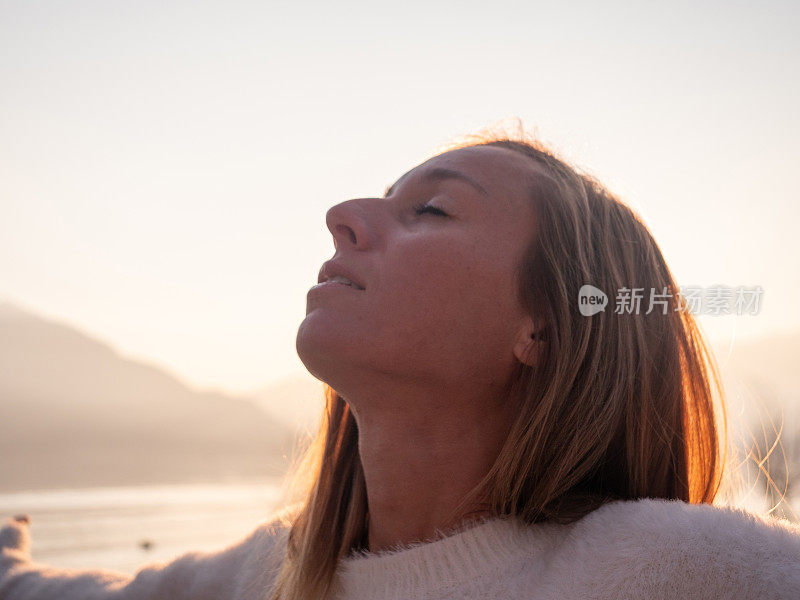 年轻女子闭眼沉思，仰望天空，满怀希望和信念