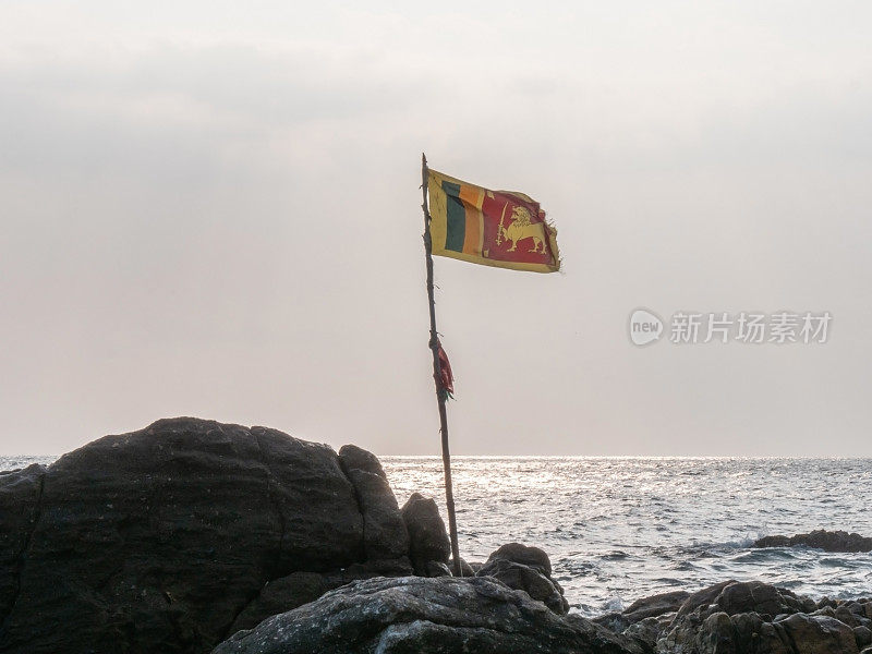 日落时斯里兰卡国旗在岩石上的海景，戏剧性的天空。没有人旅行