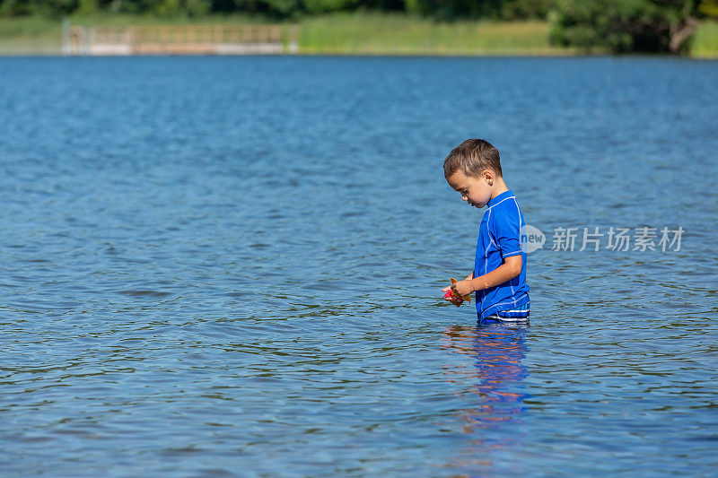 在美丽的夏日，男孩在湖水中跋涉