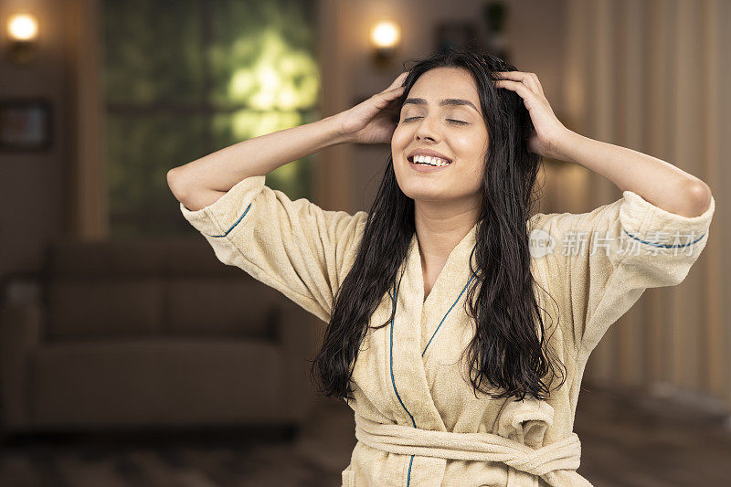 一个穿着浴袍的年轻女人在做头部按摩