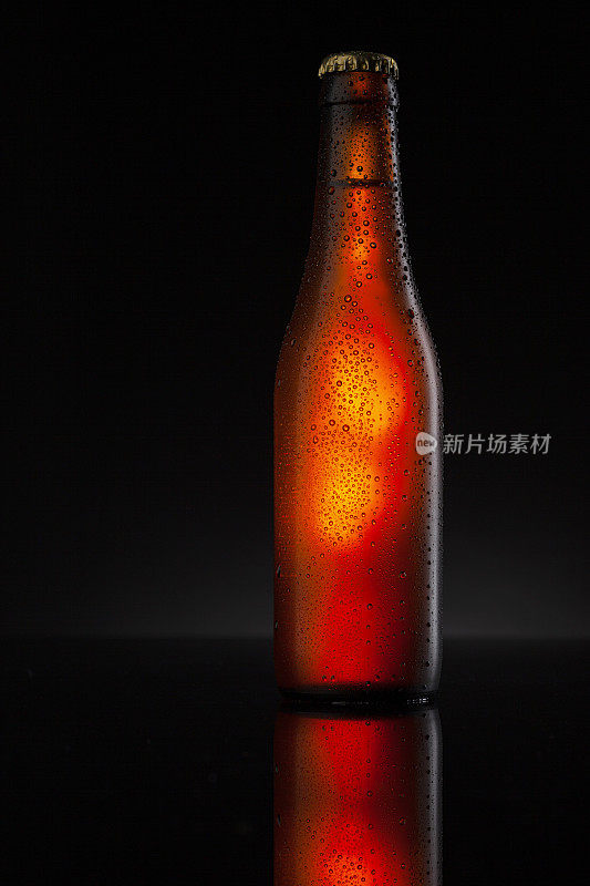 冰镇的棕色啤酒瓶覆盖着冰和水滴-凝结。用于饮料饮料产品设计模型的毛坯。站在黑色背景的黑色桌子上。
