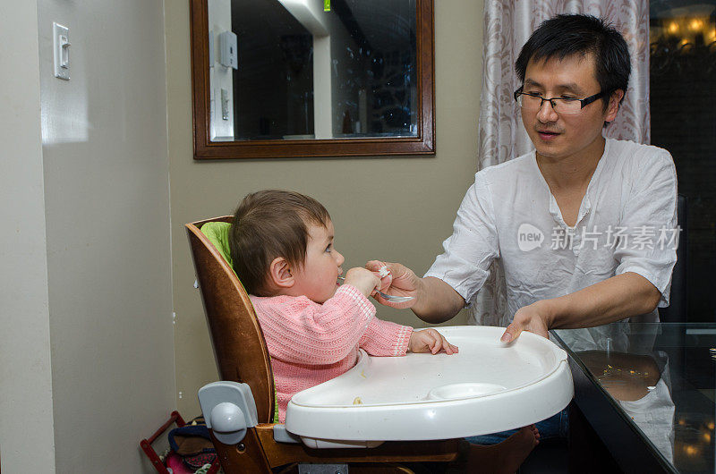 一位中国父亲正在喂养他的混血女婴