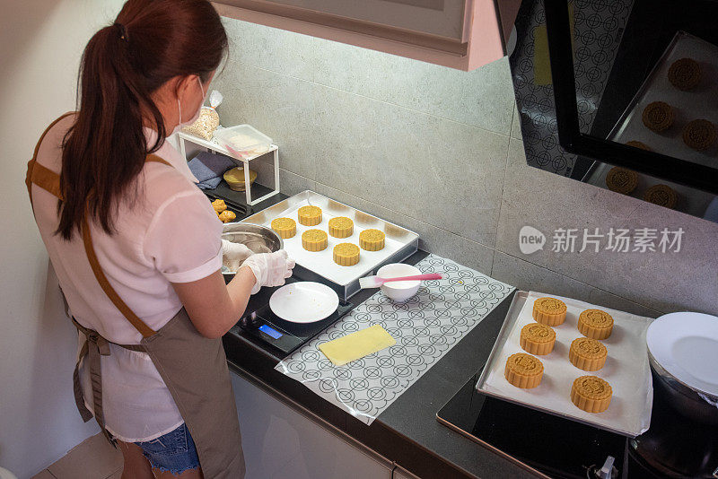 一名亚洲妇女在烘烤前在烤盘上制作自制月饼糕点的面团