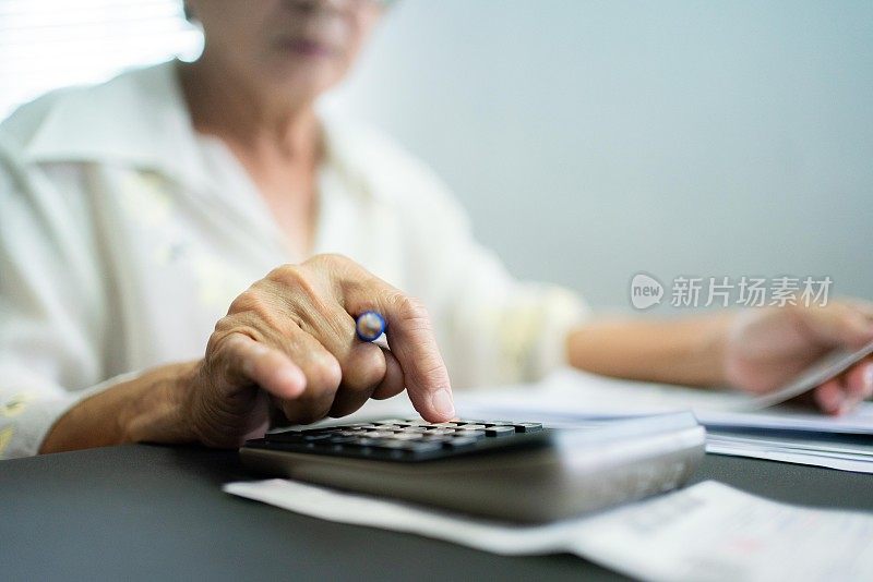 亚洲资深女性每月计算开支支票收据支付。