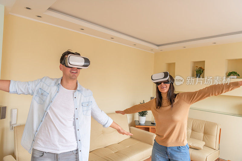 一名年轻女子和她英俊的男友戴着虚拟现实眼镜，一边玩3D游戏一边做手势。