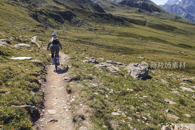 女人沿着阳光明媚的自行车道骑山地车