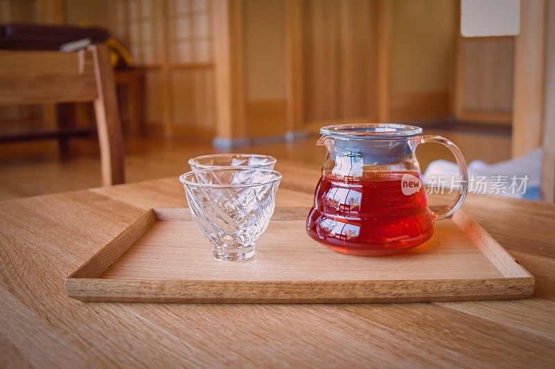 温泉浴场健身俱乐部，在极简主义的背景下，在传统的日本木制小桌上摆放着柔软的聚焦玻璃茶杯和茶壶，上面放着rooibos花草茶。健康娱乐