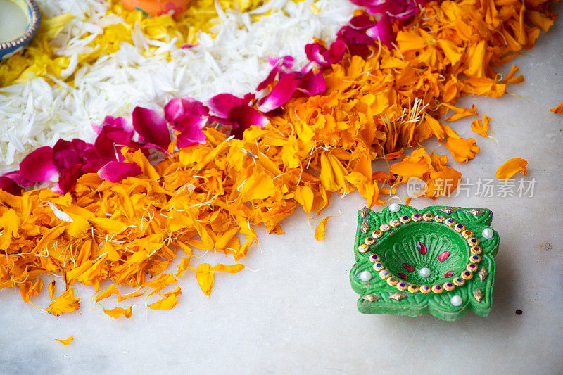 近距离拍摄的花瓣rangoli与手工绘制的陶器棕色和绿色的diya灯用于装饰印度节日排灯节，婚礼，新年