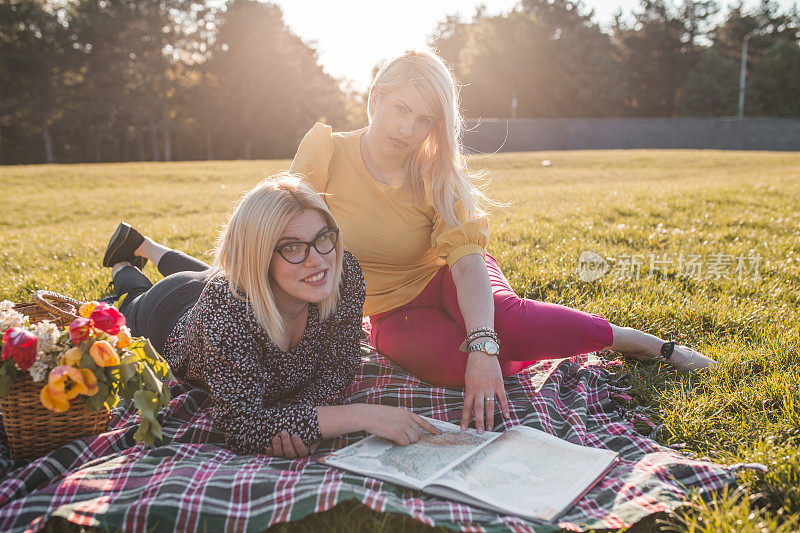 两个女人一边享受野餐，一边看地图集