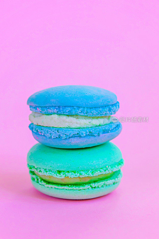 甜杏仁彩色独角兽蓝绿马卡龙或马卡龙甜点蛋糕孤立在时尚的粉红色柔和的背景。法国甜的饼干。最小的食品面包房概念复制空间