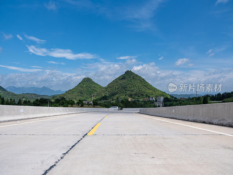 蓝天白云下，一条通往群山的空旷道路