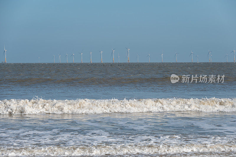 海滩、海浪和遥远的风力涡轮机