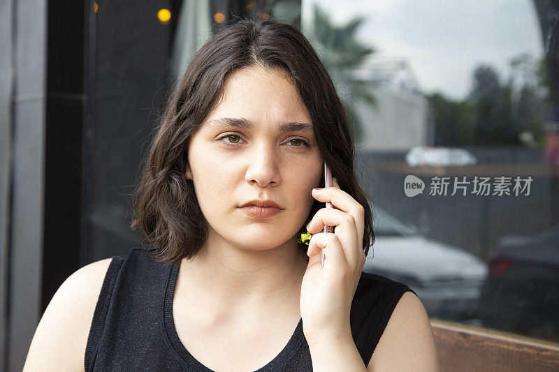 一个沮丧和心烦意乱的女人坐在咖啡馆里打电话的肖像