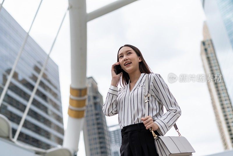 亚洲年轻漂亮的女商人在去商业区办公室的路上愉快地打电话