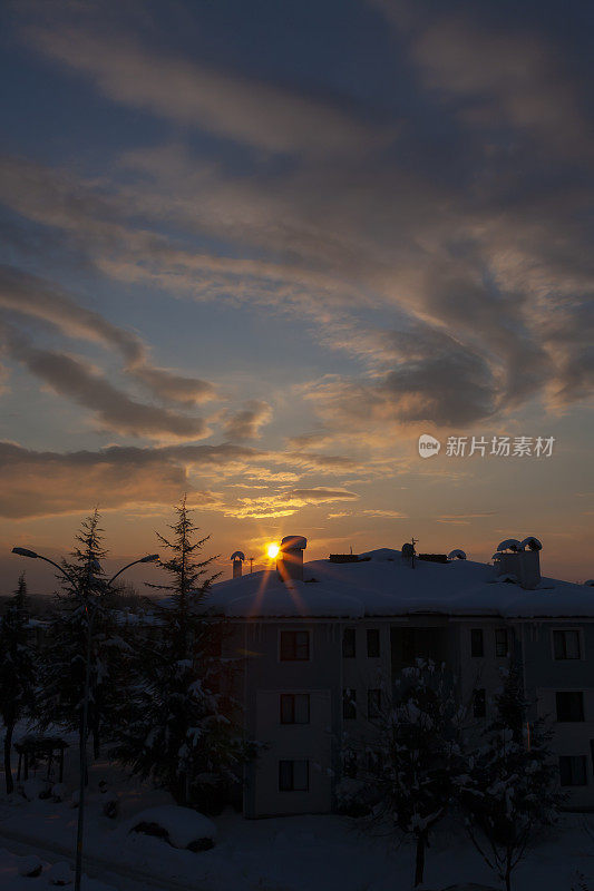 在一个下雪的冬日，夕阳和房子。