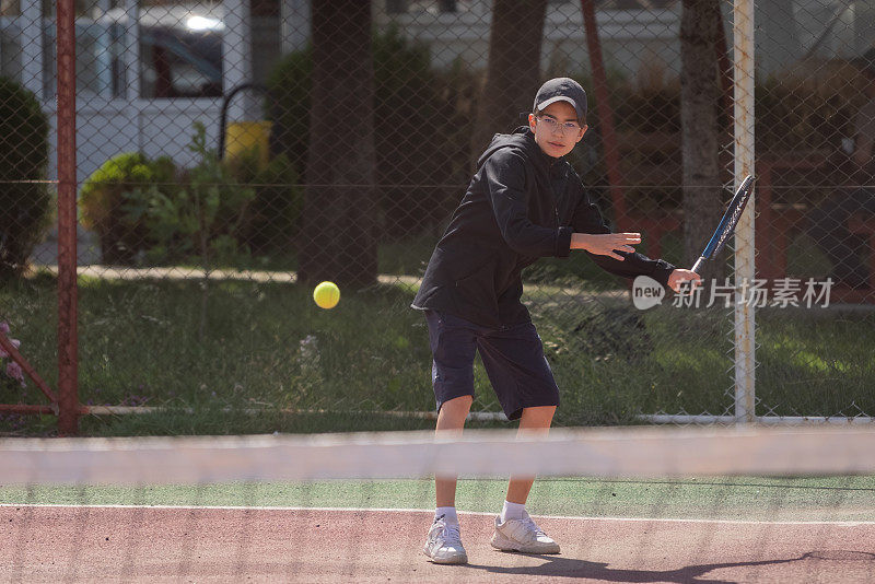 小男孩在户外球场打网球，正手打网球。