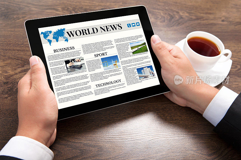 商人手持平板电脑，屏幕上显示世界新闻网站