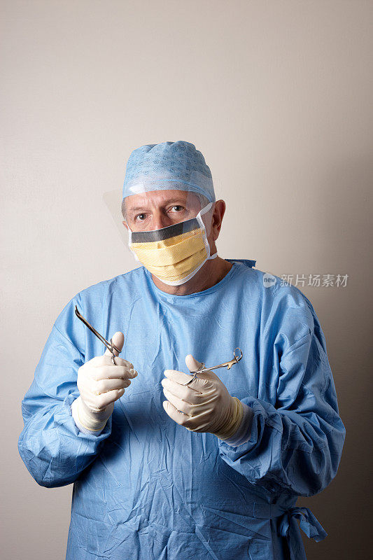 外科医生拿着钳子，穿着无菌手术服