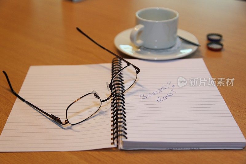 眼镜，便签本和会议上的咖啡杯