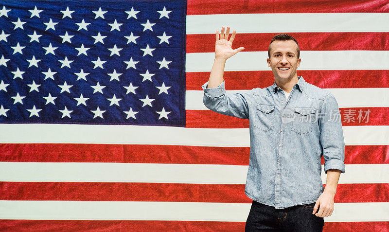 一个面带微笑的男人在美国国旗前挥手