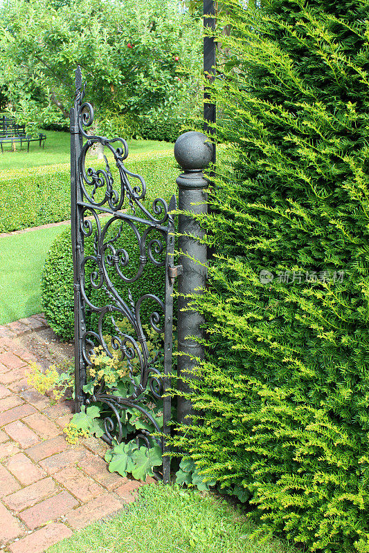 正式的花园，砖铺就的小径，华丽的铁门，紫杉树篱