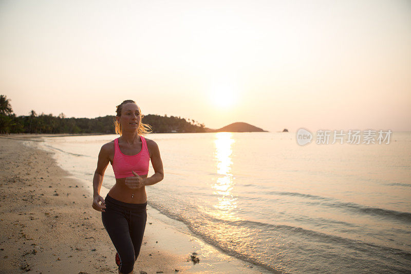 健康的女人在沙滩上跑步