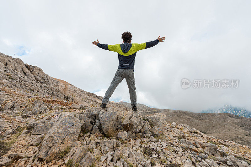 人高举双臂站在山上