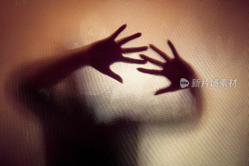 一个女人用手压在玻璃窗上的诡异剪影
