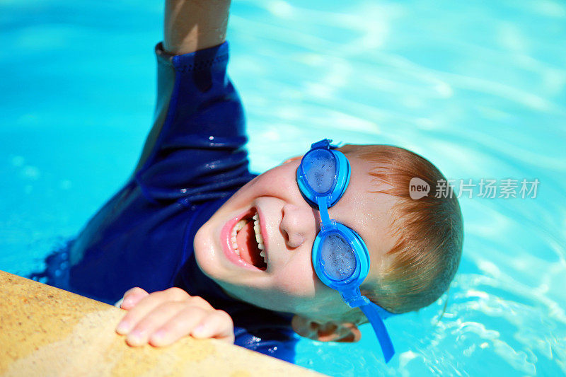 快乐的孩子戴着泳镜在游泳池里