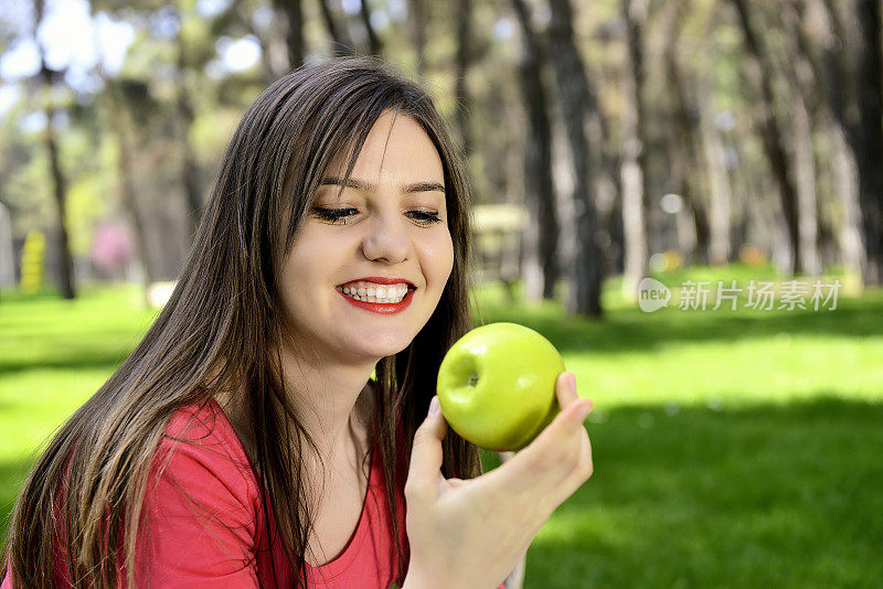 美丽的女人在户外运动后拿着苹果。
