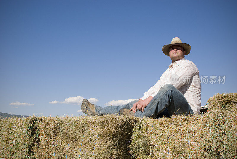牛仔农夫坐在干草堆上