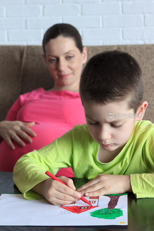 怀孕的母亲和儿子在家画画