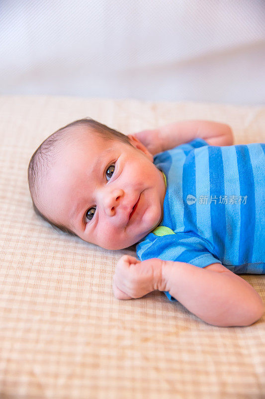 刚出生的男婴微笑着躺在婴儿床上