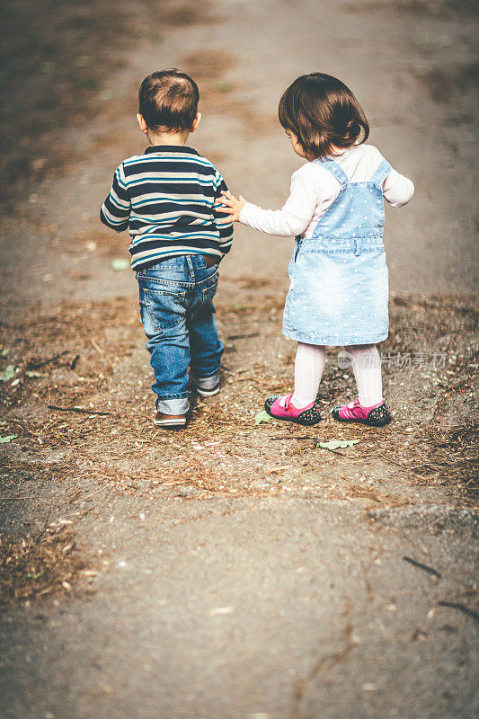 一个小男孩和一个小女孩在街上散步